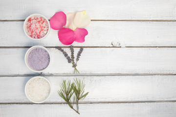 Aromas of bath salt. Rose, lavender and pine near bowls with colorful bath salt on light wooden background top view copy space