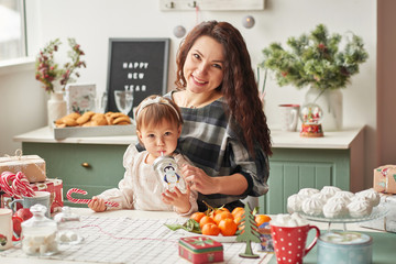 mom and little daughter in the kitchen decorated for the new year and christmas
