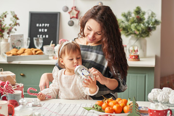 mom and little daughter in the kitchen decorated for the new year and christmas