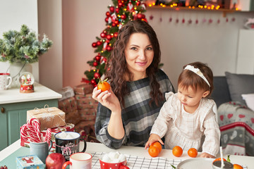 mom and little daughter in the kitchen decorated for the new year and christmas