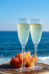Champagne, prosecco or cava served with pink grape in two glasses on outside terrace with sea view