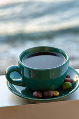 Cup with black coffee served outside with sea view