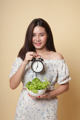 Young Asian woman with clock and salad.