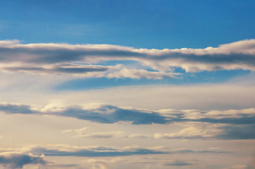Horizontal lines of white clouds on blue sky, background