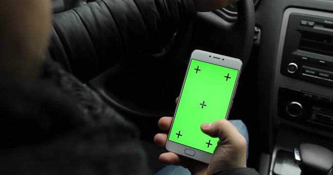 Man holding empty green screen of smartphone in car, chroma key