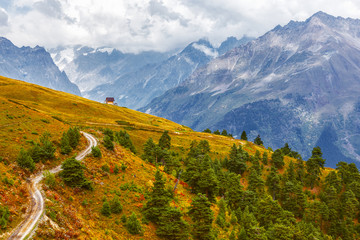 autumn landscape, path to a small house on the background of mountains.