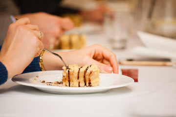 A young girl eats a dessert - a cake during a conference at the hotel 