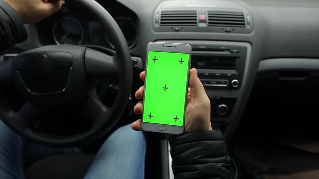 Man holding empty green screen of smartphone in car, chroma key