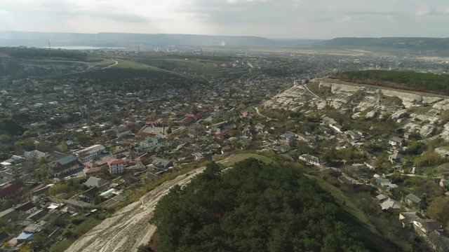 A city in lowland near the cliffs covered by pines. Shot. Aerial view