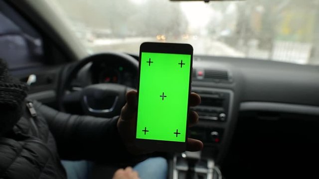 Man demonstrating empty green screen of smartphone in car, chroma key