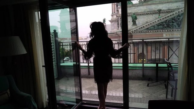 Young sexy brunette woman in lingerie staying in bedroom near window and posing. Flirting of lovely female in hotel room. Slowmotion. Dancing slow dance silhouette. Waking up in the morning