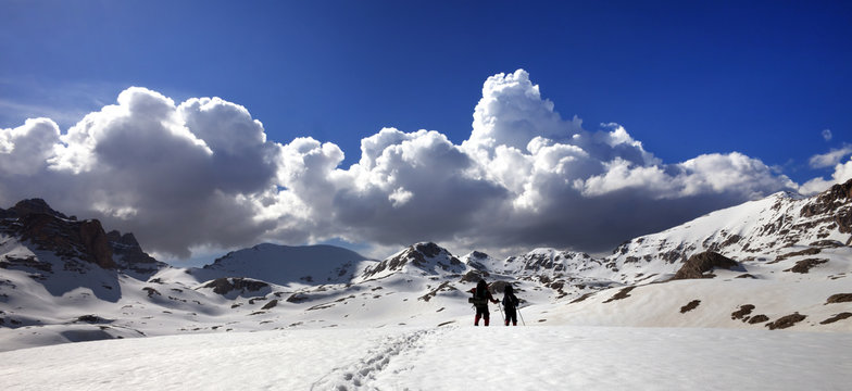 Panoramic view on snowy plateau with two hikers and blue sky