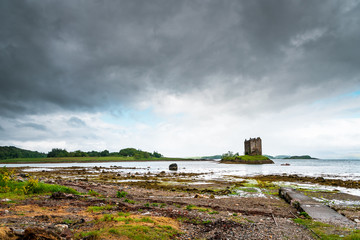 Fototapeta na wymiar Mystical Castle Stalker on an islet on Loch Laich, cloudy day and low tide, scary and lost castle in Scotland, Great Britain