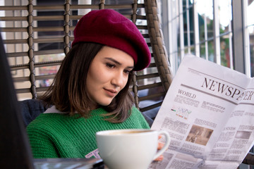 beatiful woman reading newspaper at cafe.