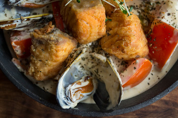 The salmon fillet and mussels in a cream sauce, close up.
