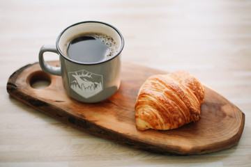 Mug of hot coffee and croissant on a wooden tray. breakfast concept. 