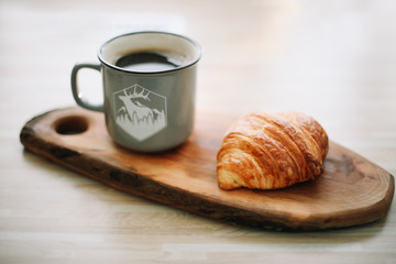 Mug of hot coffee and croissant on a wooden tray. breakfast concept. 
