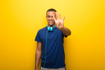 African american man with blue t-shirt on yellow background happy and counting four with fingers