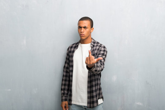 Young african american man with checkered shirt making horn gesture