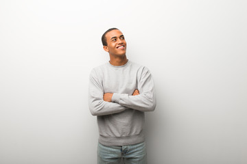 African american man on white wall background looking up while smiling