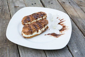 Eclairs on white plates on wooden background