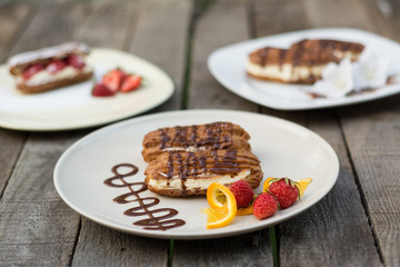 Eclairs on white plate on wooden background