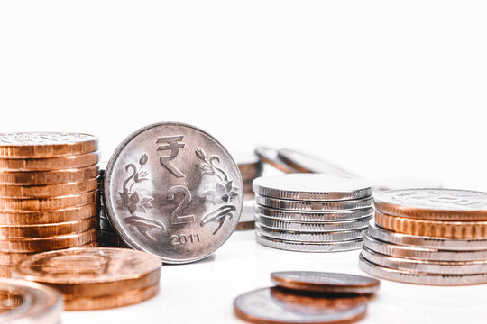 Stacks of coins and Indian rupees on a white background