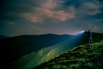 Searching with flashlight in mountains - obrazy, fototapety, plakaty