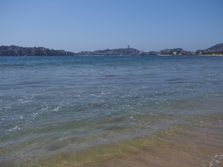 Calm sandy beach at bay of ACAPULCO city in Mexico and surface of Pacific Ocean landscape