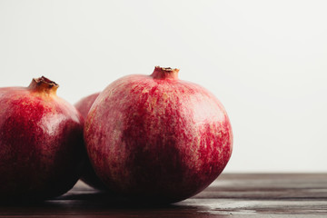 Group of pomegranate fruits on the dark wooden planks and white background