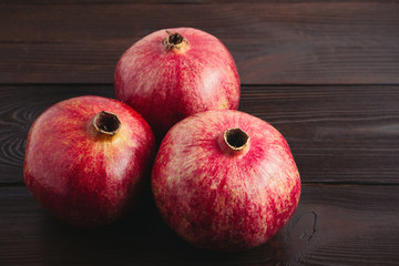 Group of pomegranate red fruits on the dark wooden background