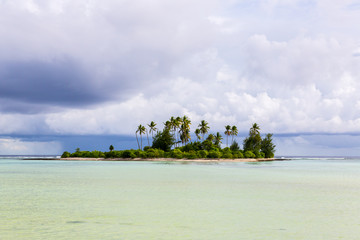 A small islet (motu) overgrown with palm forest somewhere in the lagoon of South Tarawa atoll in bad cloudy weather, Kiribati, Micronesia, Oceania.