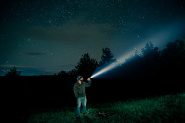 Man searching with flashlight in outdoor by night - obrazy, fototapety, plakaty
