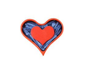Red painted wooden heart enclosed with blue paper raffia strips in box isolated on white background