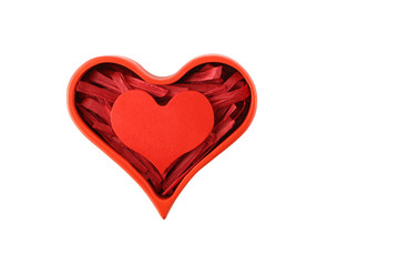 Red painted wooden heart enclosed with paper raffia strips in box isolated on white background