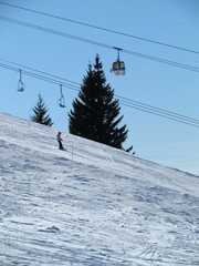 Fototapeta na wymiar Winter day Snowy alpine mountains. Skier skiing downhill. cable cars above.