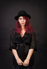 Emotional brunette in a hat with long hair posing in the Studio.