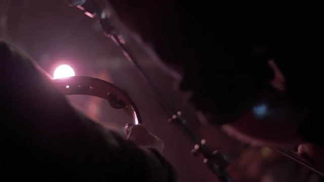 Close up, person plays tambourine in slow motion