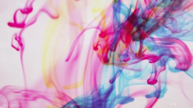 Red blue and yellow ink mixing together underwater as it spirals around making new colors.