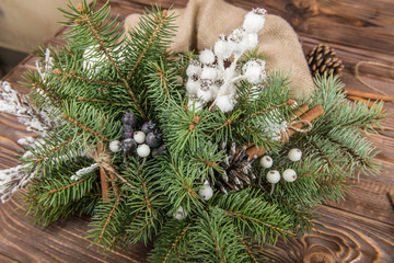 Wreath. Christmas winter frame on dark wooden background. Fir cones and cotton. Wooden toy deer