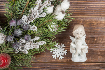 Wreath. Christmas winter frame on dark wooden background. The figure of a little angel with a bear in his hands. Christmas decorations