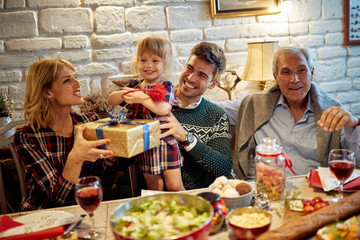 family are having dinner at home. Celebration holiday and exchange present together.