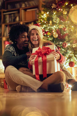 Smiling man and woman exchanging Christmas presents .