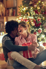 Romantic man and woman opening a present on a Christmas.