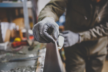 A man repairman in workshop ski service repairing the sliding surface of the ski at Ski vise. In...