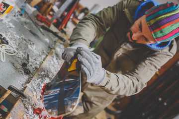 Male worker repairing Stone, edge sharpening in ski service workshop, sliding surface of the skis....