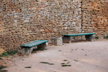 bench near ancient wall paved with bricks in park 