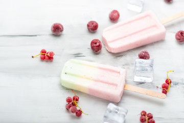 Popsicles on a stick. Bright color, summer mood. Eskimo berry with berries and ice on a light background. Flat-lay