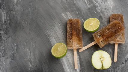 ice cream flavored soda, cola on a stick. Bright color, summer mood. Eskimo with lime and apple, refreshing on a dark background. Flat-lay