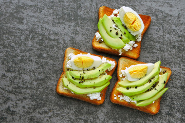 Appetizing avocado toasts with curd and egg.